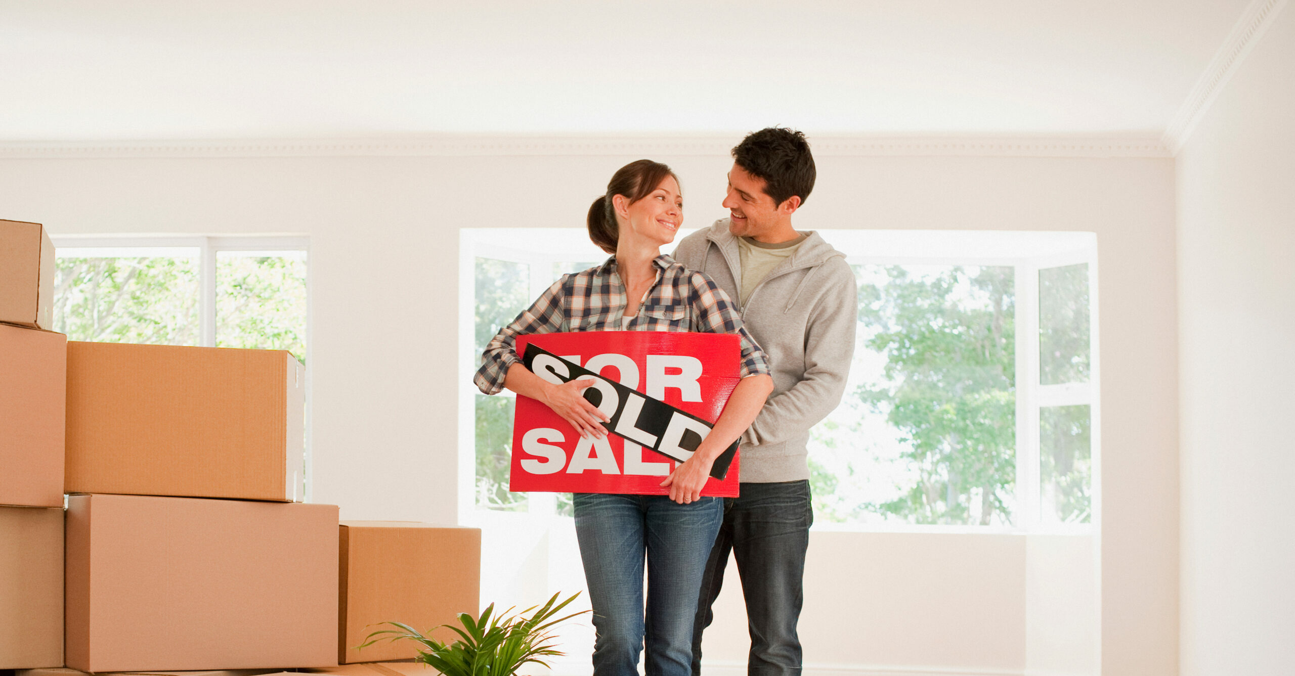Couple holding sold sign for their new house